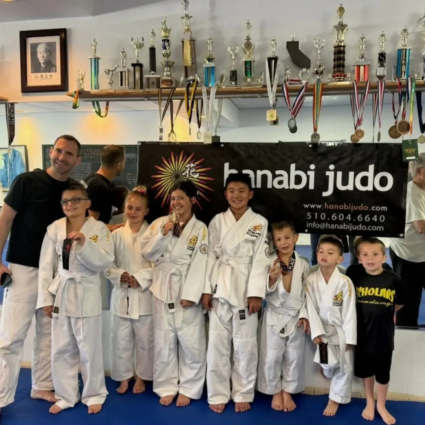 Young judo students posing with medals and an instructor after a martial arts event in Brentwood, CA