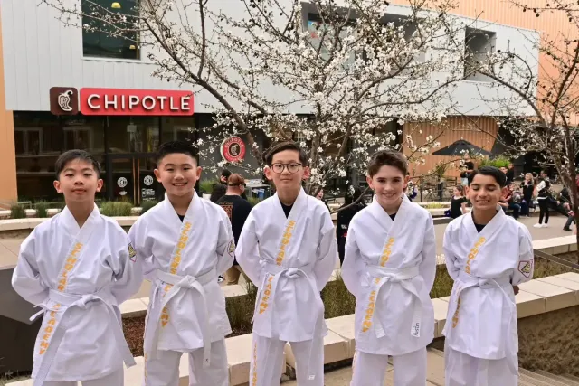 Five people in white martial arts uniforms standing outside a Chipotle restaurant
