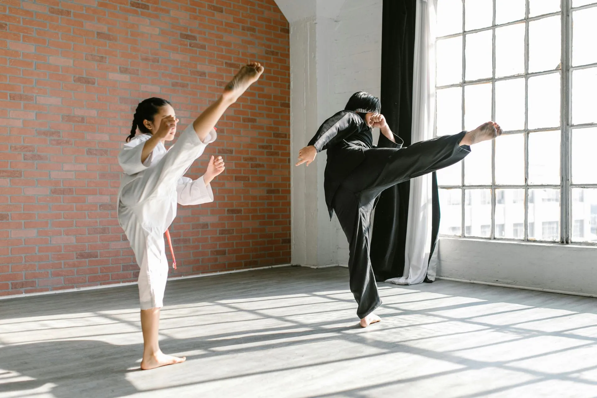 A man and a woman are practicing karate in a gym.