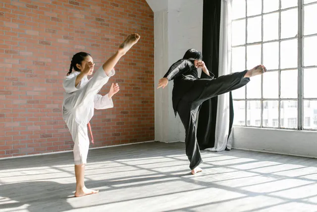 A man and a woman are practicing karate in a gym.